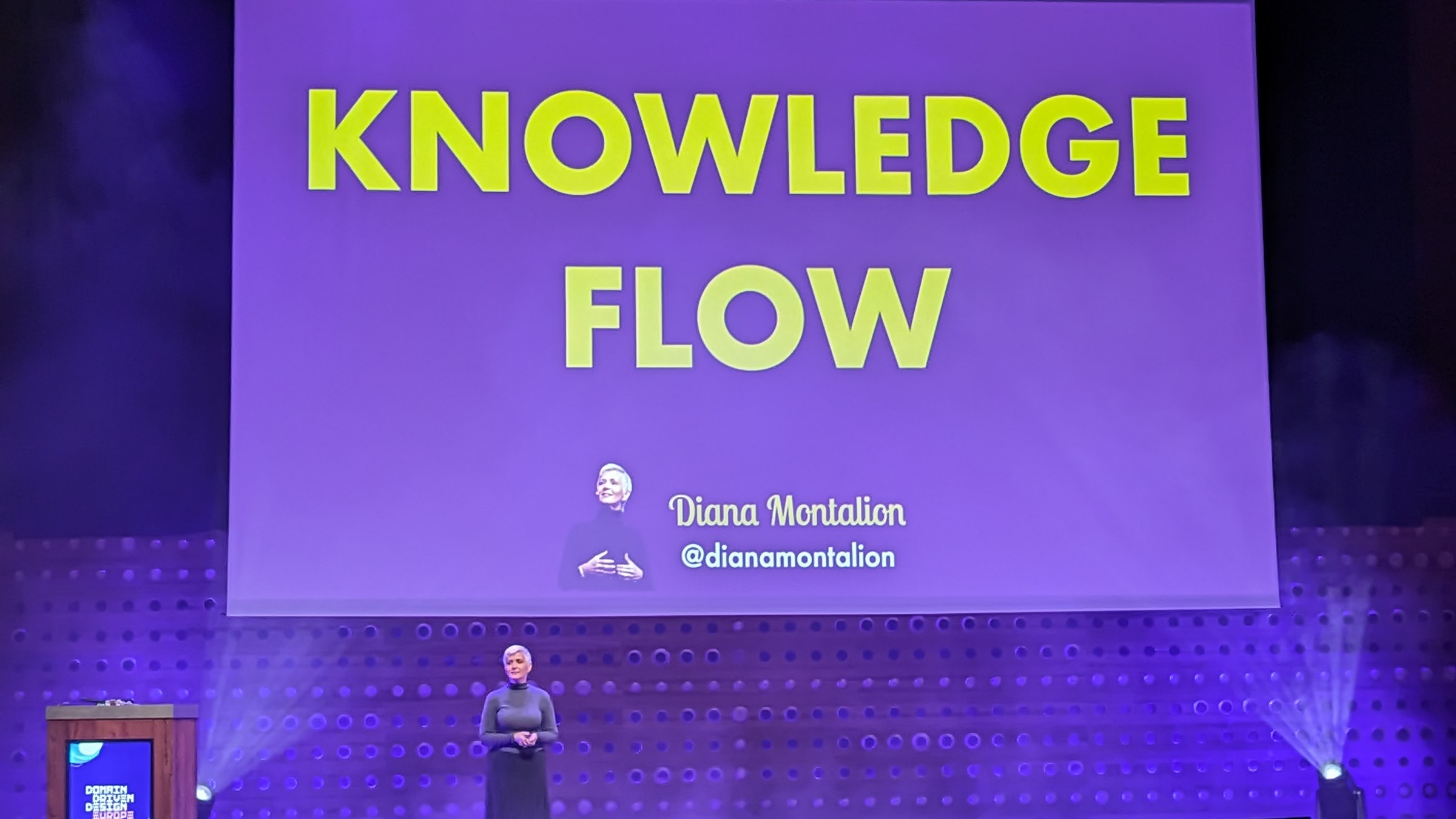 Diana at the bottom left in front of a slide reading: Knowledge is engineered through learning'