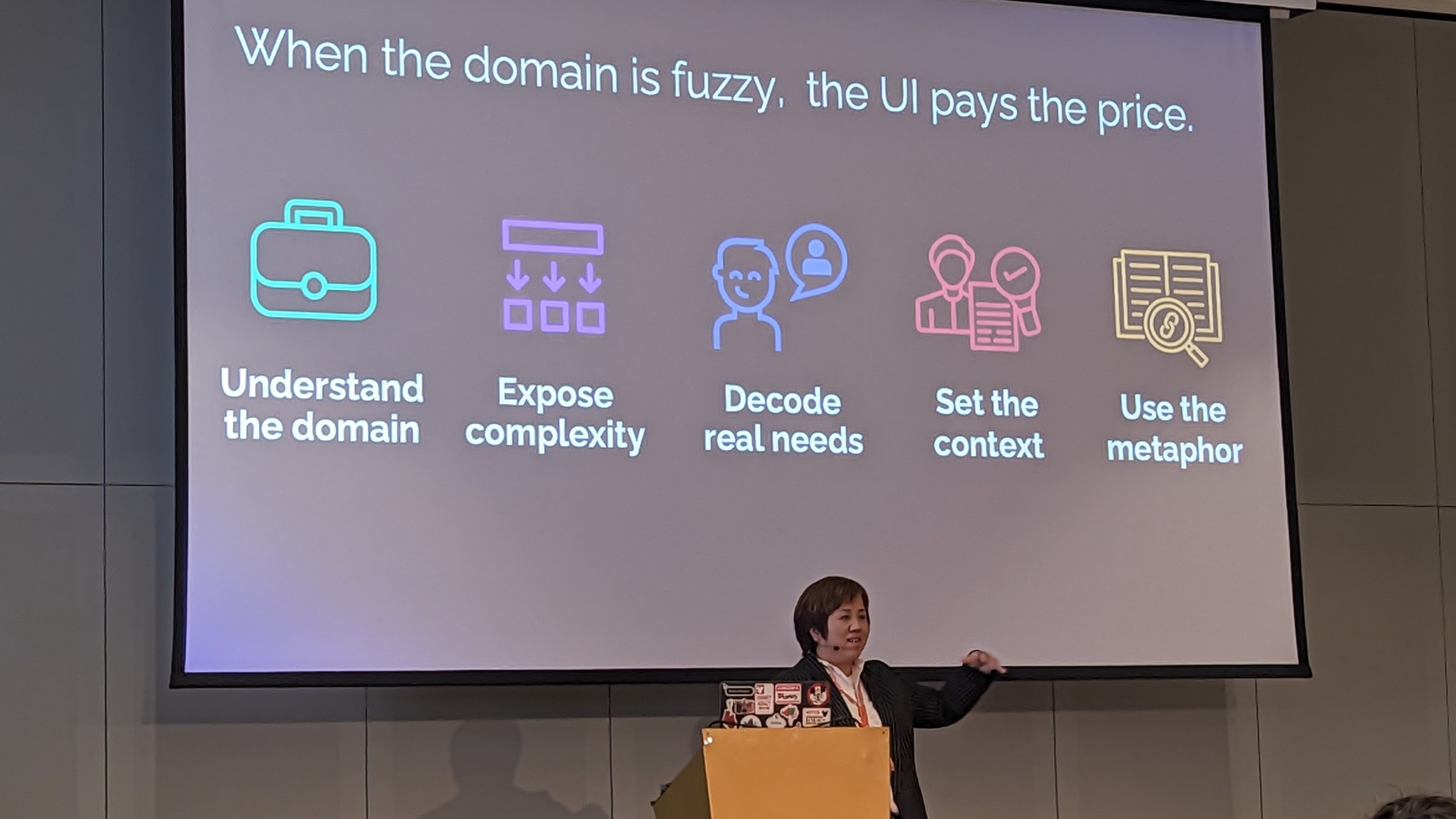 Frances in front of a slide reading:
When the domain is fuzzy, the UI pays the price
- Understand the domain
- expose complexity
- decode real needs
- set the context
- use the metaphor